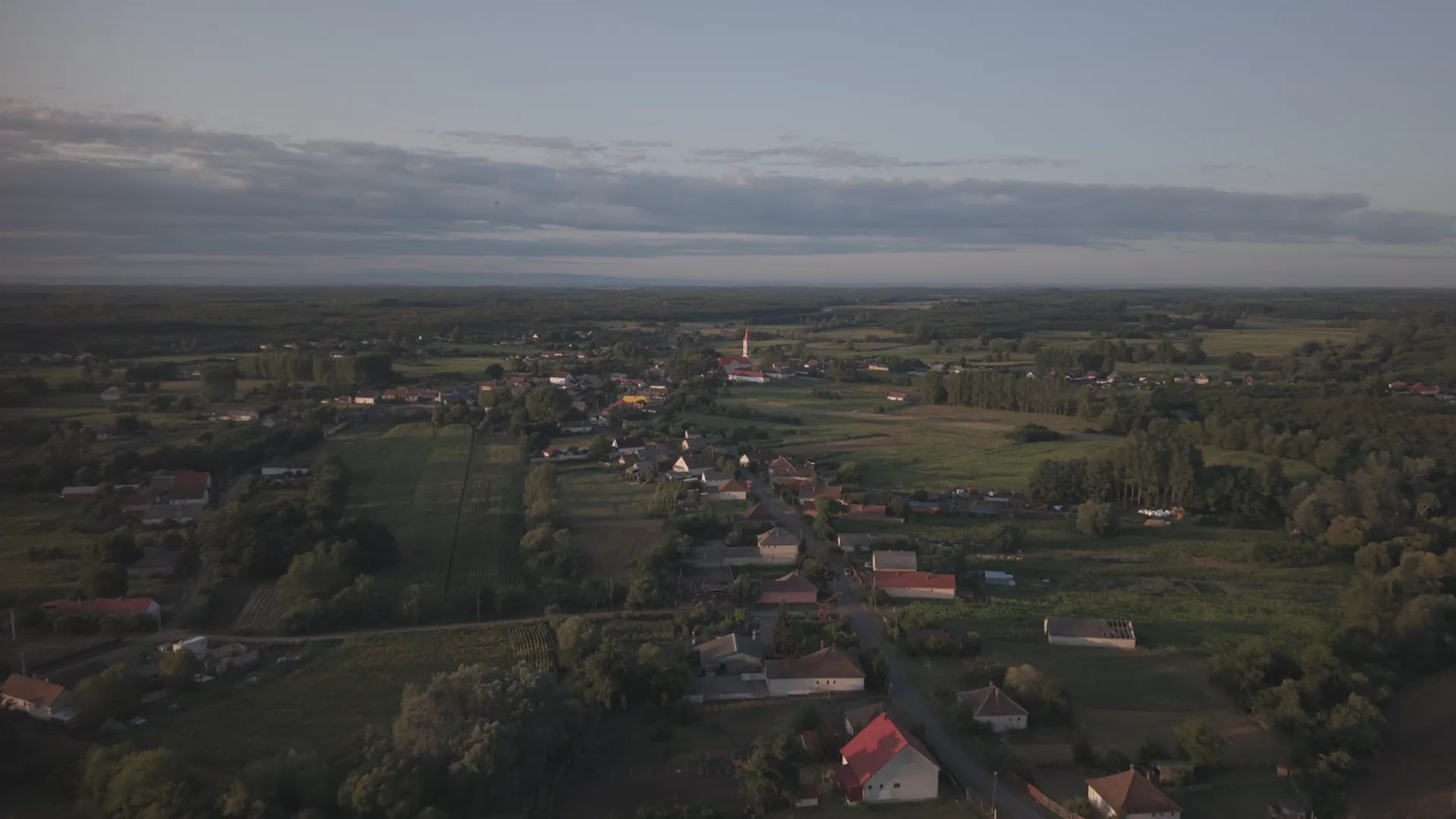 Légi felvétel Penészlekről alkonyatkor: templomtorony, házak és a környező szántók.